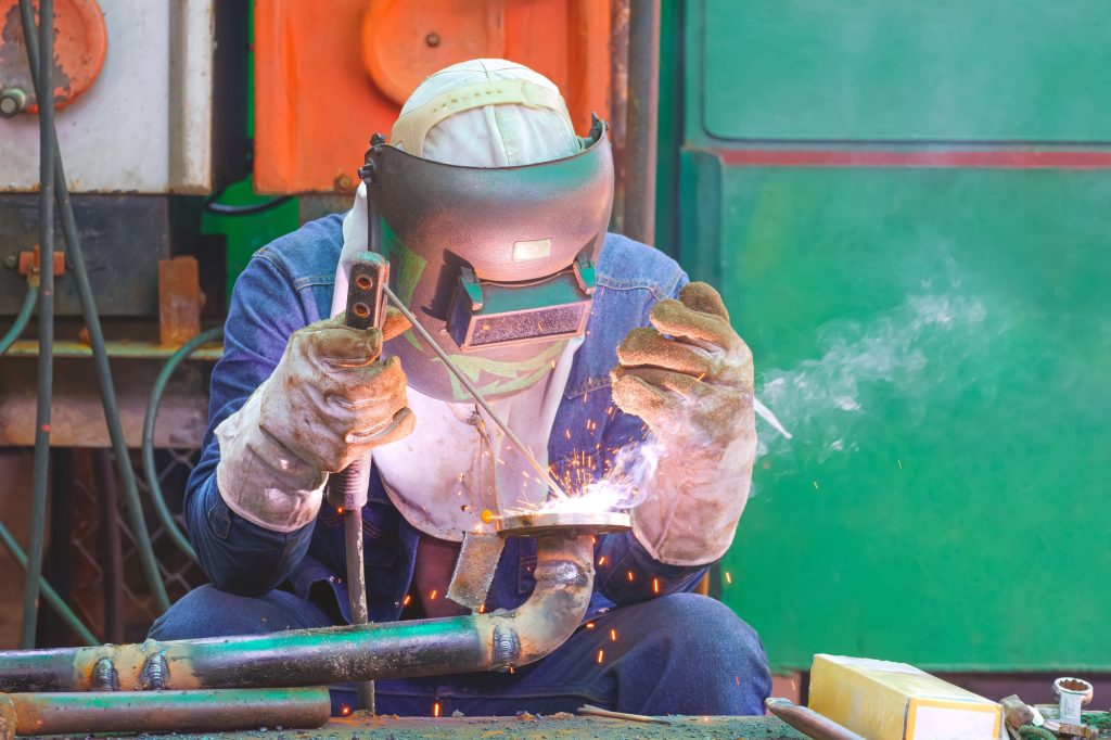 Welder welding metal flange to connect with pipe for using in oil pipeline system improvement work